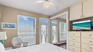 A bedroom with a bed, a television, a chair, and a wardrobe. - Destiny Beach Villas #9B (Destin)