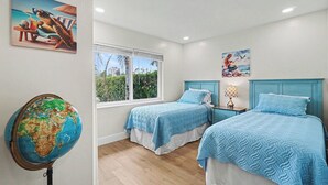 Une chambre avec deux lits, un globe terrestre et des œuvres d’art sur le thème de la plage.