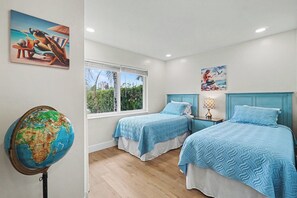 Ein Schlafzimmer mit zwei Betten, einem Globus und Strandmotiven.