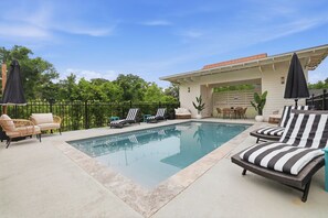 Ein Schwimmbecken mit Liegestühlen und einer überdachten Terrassenanlage.
