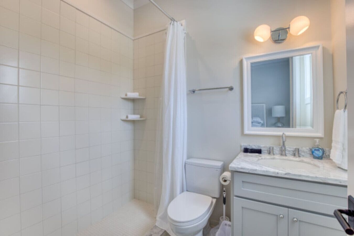 Une salle de bain équipée d’une douche, de toilettes, d’un lavabo et d’un miroir.