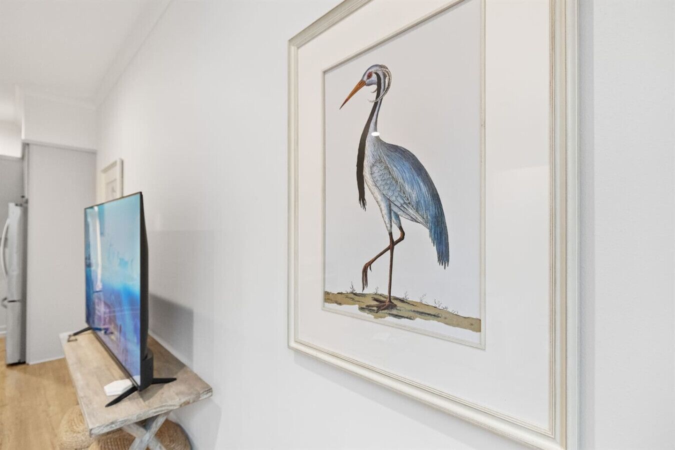 A framed artwork of a bird on a wall.