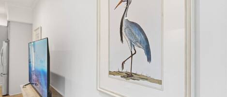 A framed artwork of a bird on a wall.
