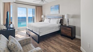 A spacious bedroom with a large bed, a nightstand, a dresser, and a view of the ocean through a sliding glass door. - Ariel Dunes I 2301 (Miramar Beach)