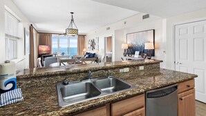 A modern kitchen with granite countertops, stainless steel sink, and a dishwasher. - Ariel Dunes I 2301 (Miramar Beach)