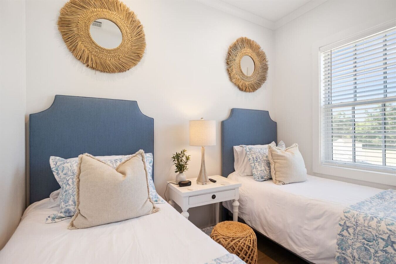 Une chambre avec deux lits, une table de chevet, une lampe et deux miroirs ronds fixés au mur.