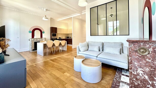 A modern living room with a sofa, a dining area with chairs, a kitchen in the background, and a large mirror on the wall. - Le Bastille / 6 pers / 300 m station / Air-conditioned (Grenoble)
