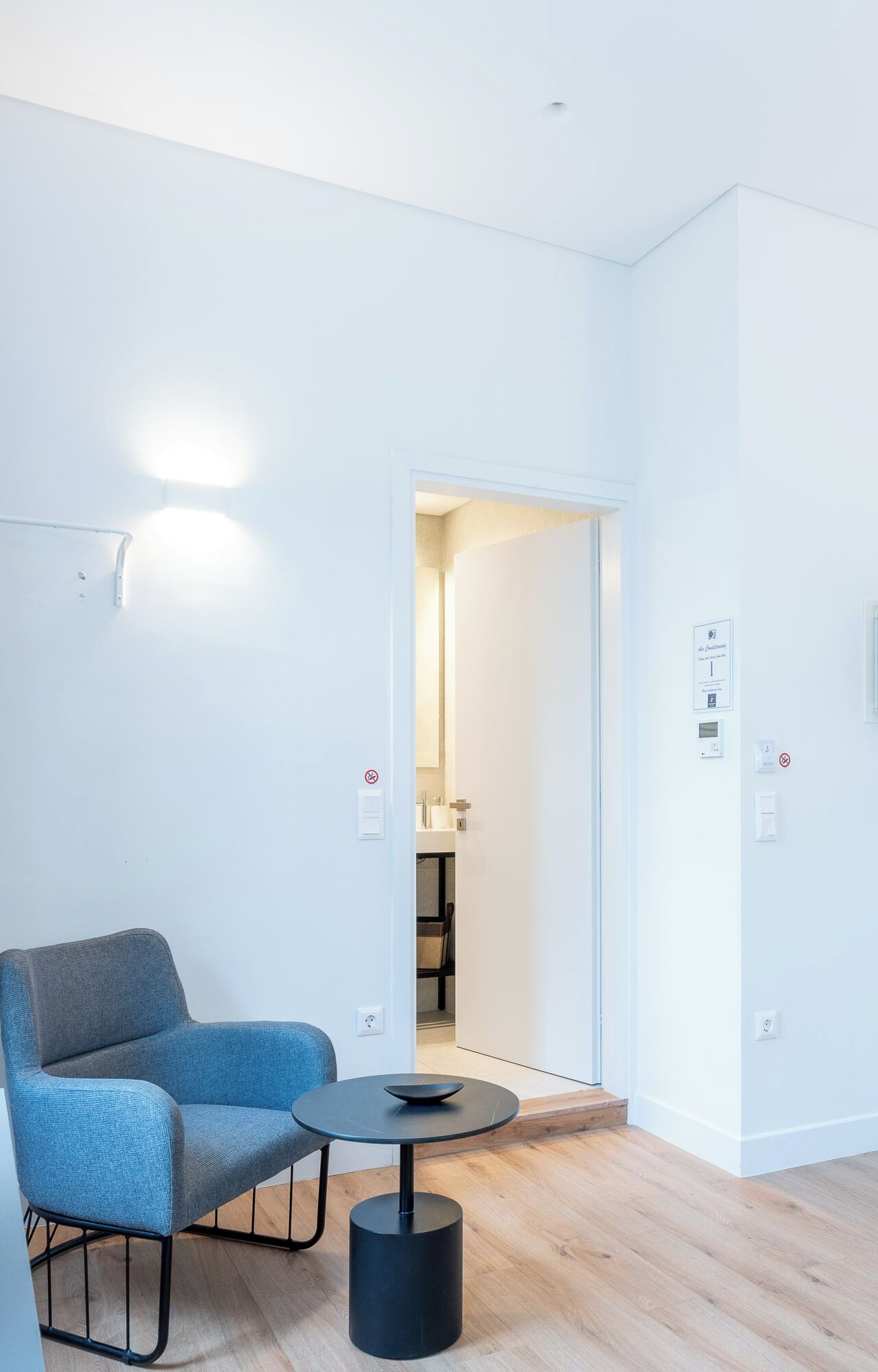 Una stanza moderna e minimalista con una poltrona blu e un tavolino rotondo.