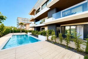 A modern apartment with a swimming pool, outdoor seating, and a balcony. - Aurora Sand 3 - Carraro Immobiliare Jesolo (Lido di Jesolo)