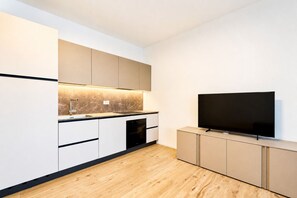 Eine moderne Küche mit Einbauofen, großem Flachbildfernseher und Marmor-Spritzschutz.