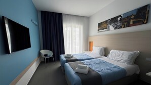 A hotel room with two beds, a flat-screen TV, a chair, and a painting on the wall.