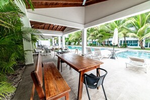 Eine Außenpatio mit Pool, Holzmöbeln und Palmen.