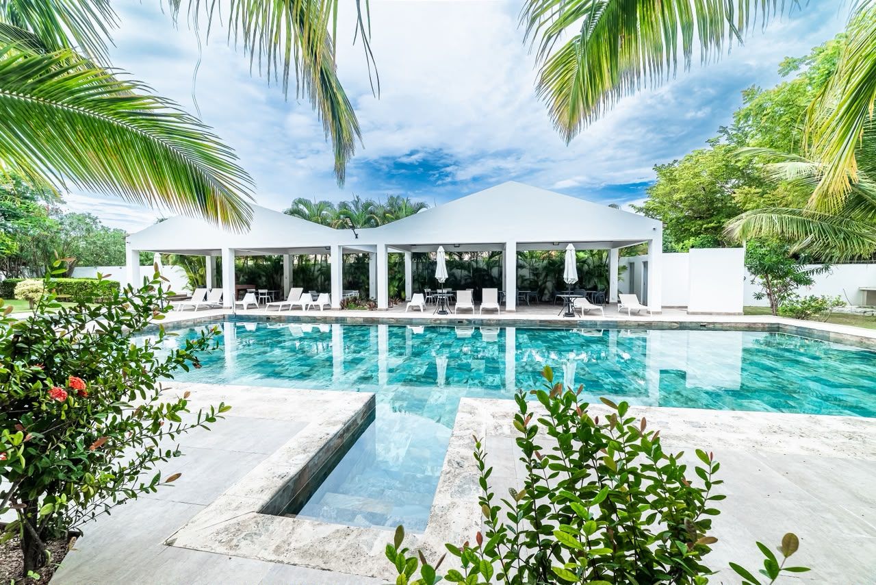 A poolside area with a clear view of the pool, lounge chairs, and a covered seating area.