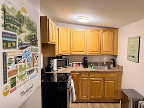 A kitchen with wooden cabinets, a microwave, a kettle, and a coffee maker.