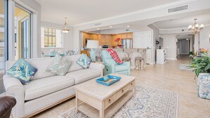 Ein geräumiges Wohnzimmer mit einer Couch, einem Couchtisch und Blick zur Küche.