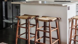 Una cocina moderna con armarios blancos, techo de madera y una isla central con taburetes de bar.