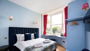 A bedroom with a bed, bedside tables, a window with curtains, and a wall-mounted lamp. - Deluxe Double Room (Room 10 - Ground Floor) (Edinburgh)