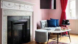 A living room with a fireplace, a sofa, a coffee table, and a television. - Deluxe Family Room (Room 12 - First Floor) (Edinburgh)