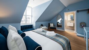 Un dormitorio moderno con una cama grande, una zona de estar, un tocador y un tragaluz.