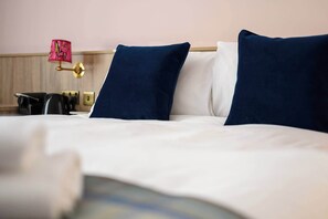 A neatly made bed with white and navy blue pillows, a bedside lamp, and a wooden headboard. - Deluxe Family Room (Room 3 - Lower Ground Floor) (Edinburgh)