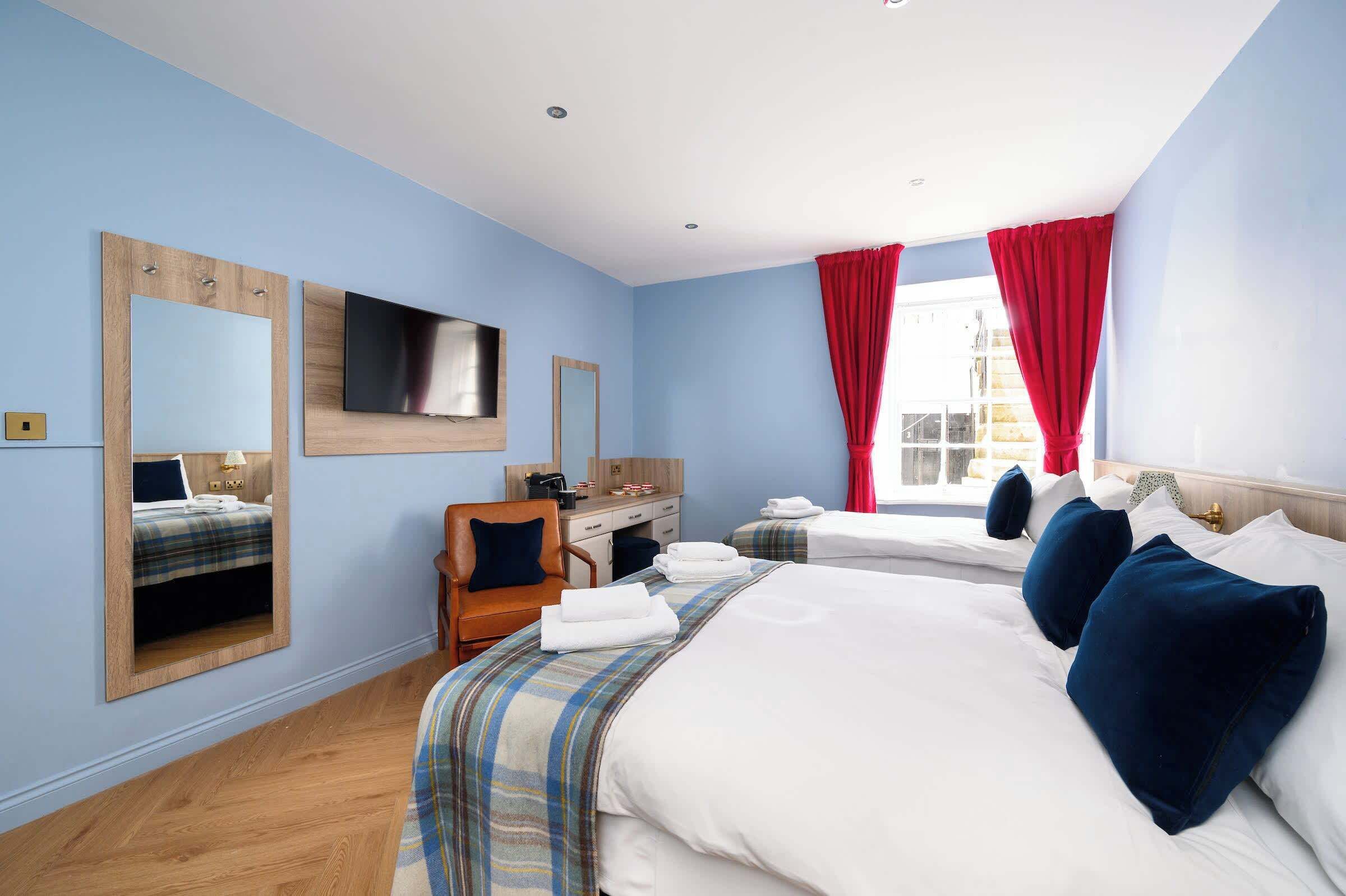 A hotel room with two beds, a desk, and a chair.