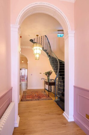 A hallway with a staircase, a chandelier, and a rug. - Deluxe Double with Bathroom (Room 5 - Ground Floor) (Edinburgh)