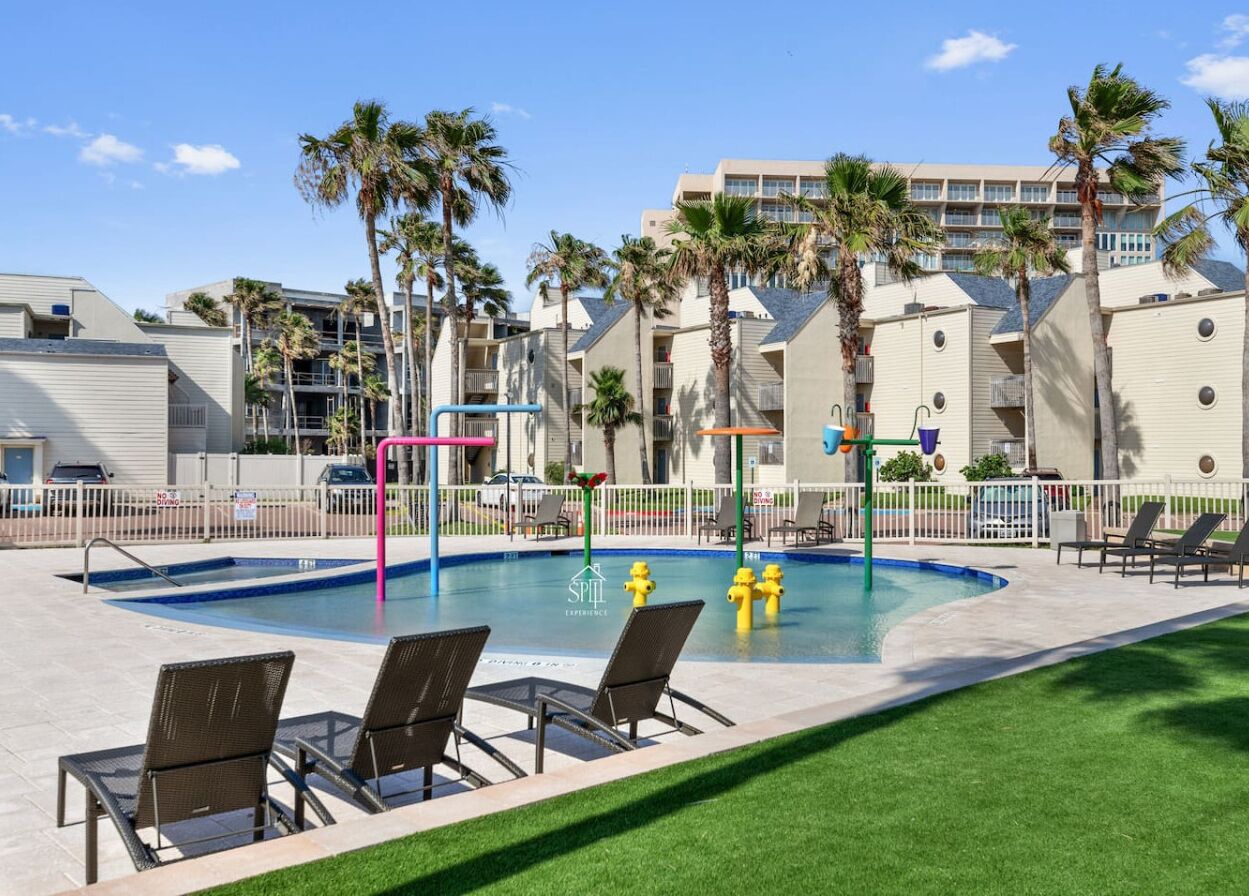 A pool area with lounge chairs, a pool, and a fence.