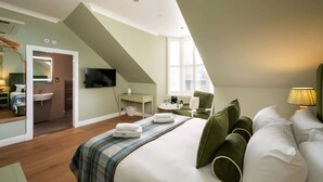 A bedroom with a bed, a TV, a desk, a chair, and a window. - Deluxe Double Room with Shower (3rd Floor - Room 12) (Edinburgh)