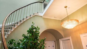 A spiral staircase with a wooden handrail, a potted tree, and a chandelier. - Deluxe Double Room with Shower (3rd Floor - Room 12) (Edinburgh)