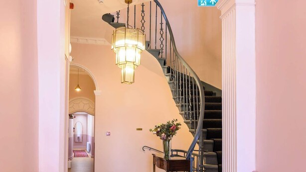 A hallway with a staircase, a chandelier, and a rug. - Deluxe Family Room (Room 8 - Ground Floor) (Edinburgh)