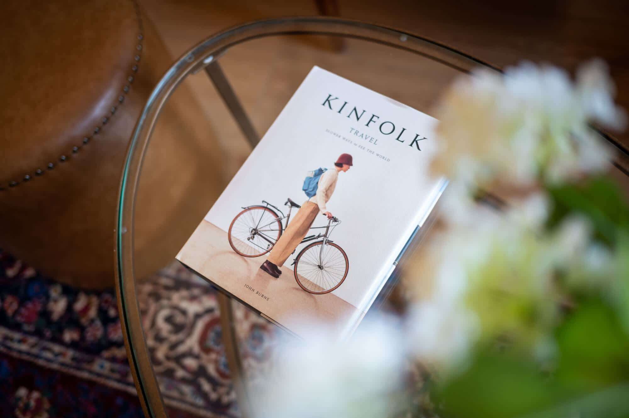 A book titled 'KINFOLK' on a glass table with a patterned rug in the background.