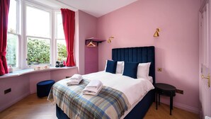 A bedroom with a bed, a window with curtains, a bedside table, and a hanging light fixture. - Deluxe Double Room (Room 9 - Ground Floor) (Edinburgh)