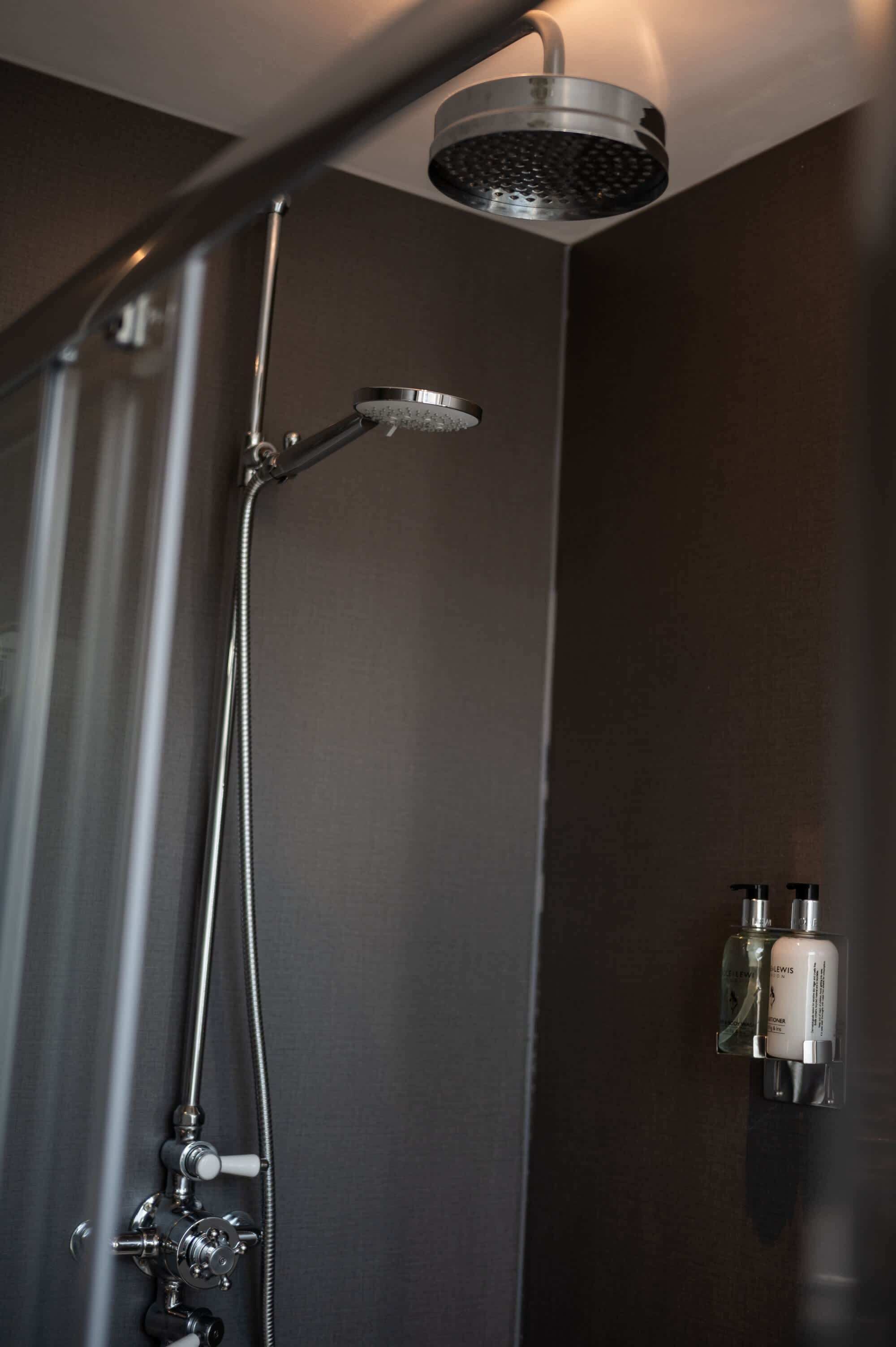 Una doccia moderna con soffione a mano e rubinetto a parete.