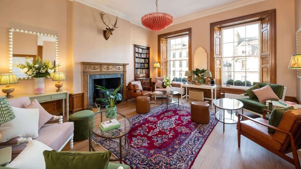 A cozy living room with a fireplace, comfortable seating, a large window, and a bookshelf. - Triple Room with Private Bathroom (2nd Floor - Room 2) (Edinburgh)