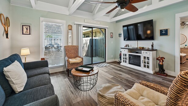 A living room with a ceiling fan, a TV, a wicker chair, a sofa, and a dining area with a cabinet. - Coastal Vibes & Community Amenities Await You! (Hilton Head Island)