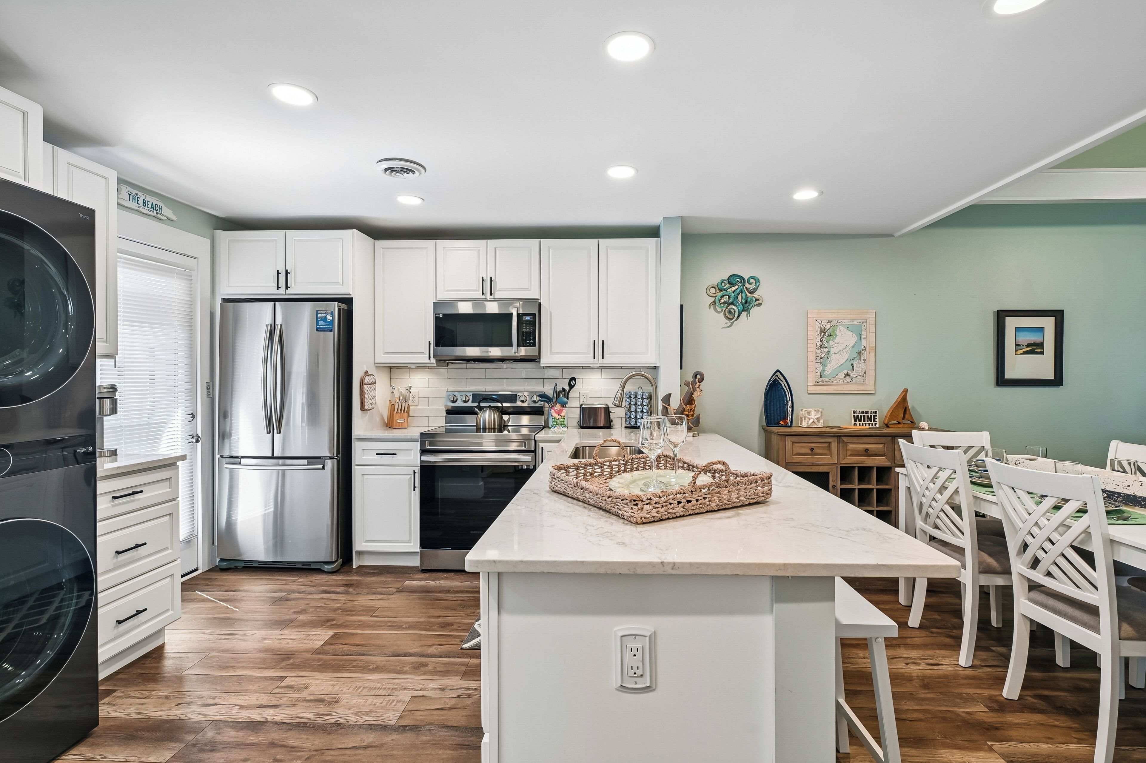 A modern kitchen with stainless steel appliances, white cabinetry, and a central island with a woven basket.