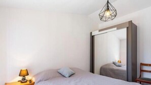 Et soveværelse med en seng, et natbord med lampe, et stort spejl og en hængende loftlampe.