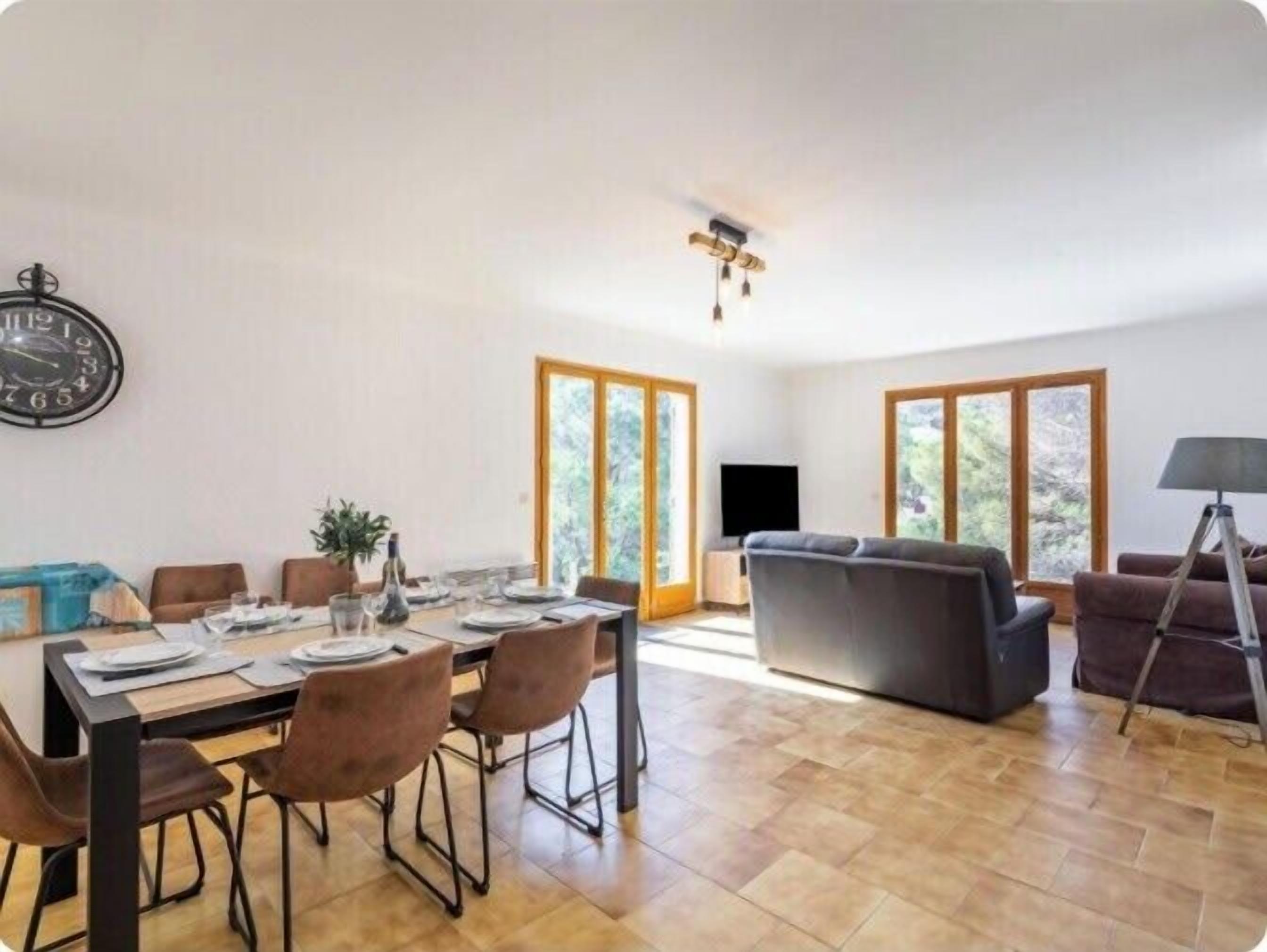A spacious living area with a dining table set for four, a sofa, and a television.