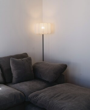 A modern living room with a grey sofa and a floor lamp.