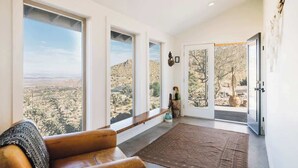 A spacious room with large windows offering a view of a desert landscape. - High Point · 6-Acres, Sweeping Views, Hot Tub (Joshua Tree)