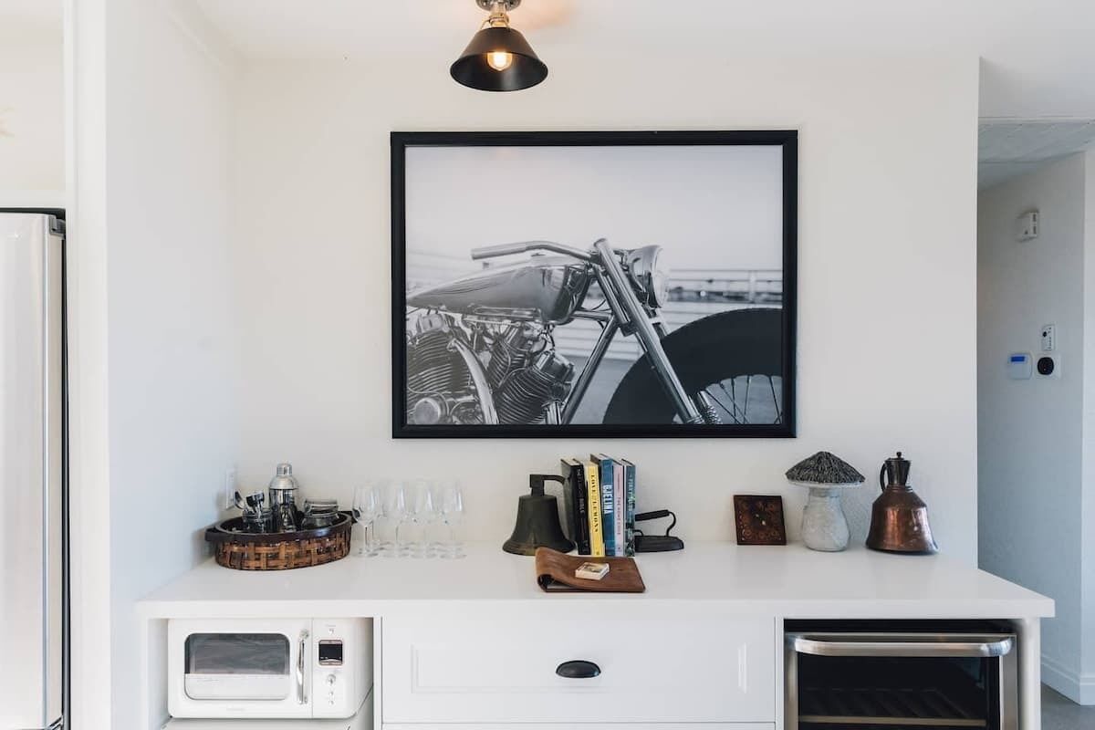 A kitchen with a white countertop, a microwave, a coffee maker, and a framed black and white motorcycle photo above it.