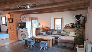 Un salon chaleureux avec un plancher en bois, un ensemble de canapés, une table basse et un téléviseur.