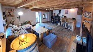 Un intérieur chaleureux et rustique, avec un plafond en bois, une cheminée, un coin repas et un bar.