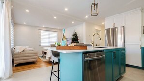 A modern kitchen with a central island, stainless steel appliances, and teal cabinetry. - 2-bedroom condo in beautiful Montréal I Bright, Modern & Cozy (Montréal)