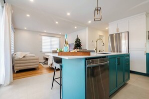 Une cuisine moderne dotée d’un îlot central, d’appareils électroménagers en acier inoxydable et de meubles de couleur turquoise.