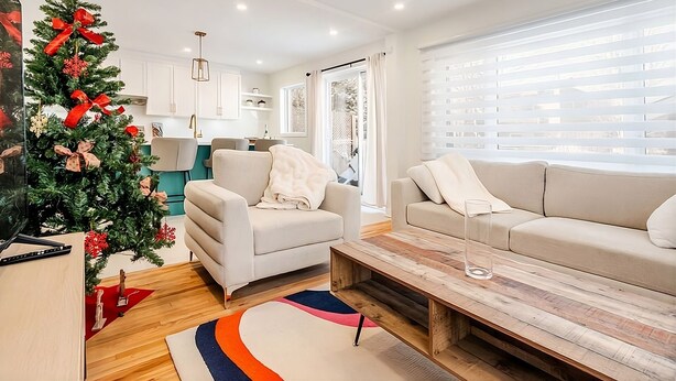 A modern living room with two sofas, a coffee table, and a Christmas tree. - 2-bedroom condo in beautiful Montréal I Bright, Modern & Cozy (Montréal)