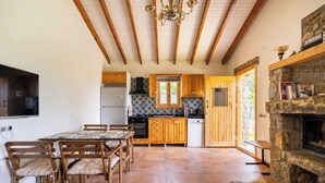 A rustic kitchen with wooden cabinets, a stone fireplace, and a dining area with a table and chairs. - Detached Single - Storey Stone house in Datça Karaincir - Karaincir Houses 1 (Datça)