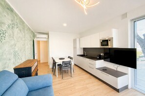 Una cocina moderna con gabinetes blancos, un microondas y un televisor de pantalla plana.