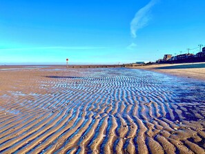 A beach with rippled sand patterns and a red flag marker.