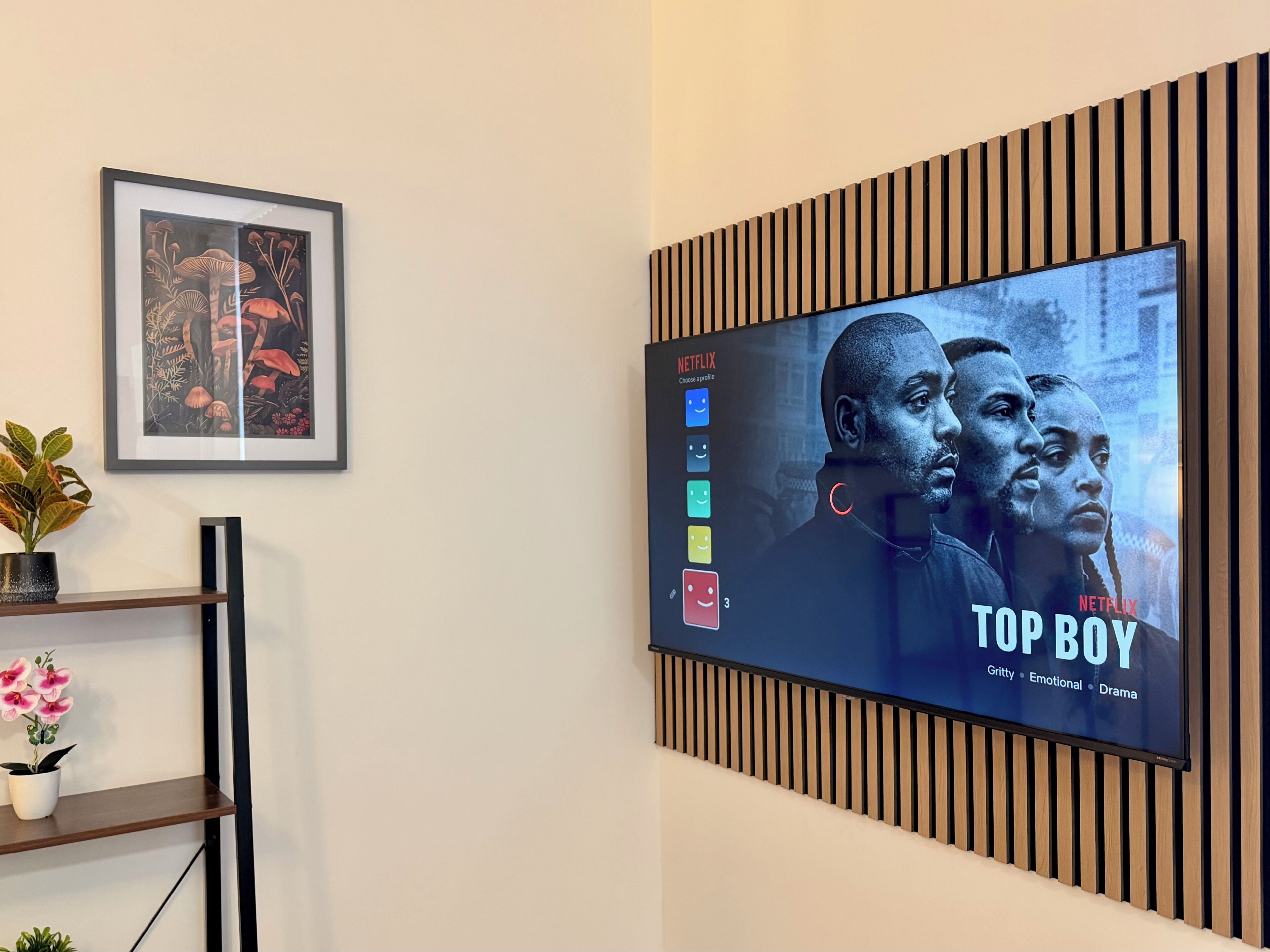 A wall-mounted television displaying the Netflix show 'Top Boy' with a profile selection interface.